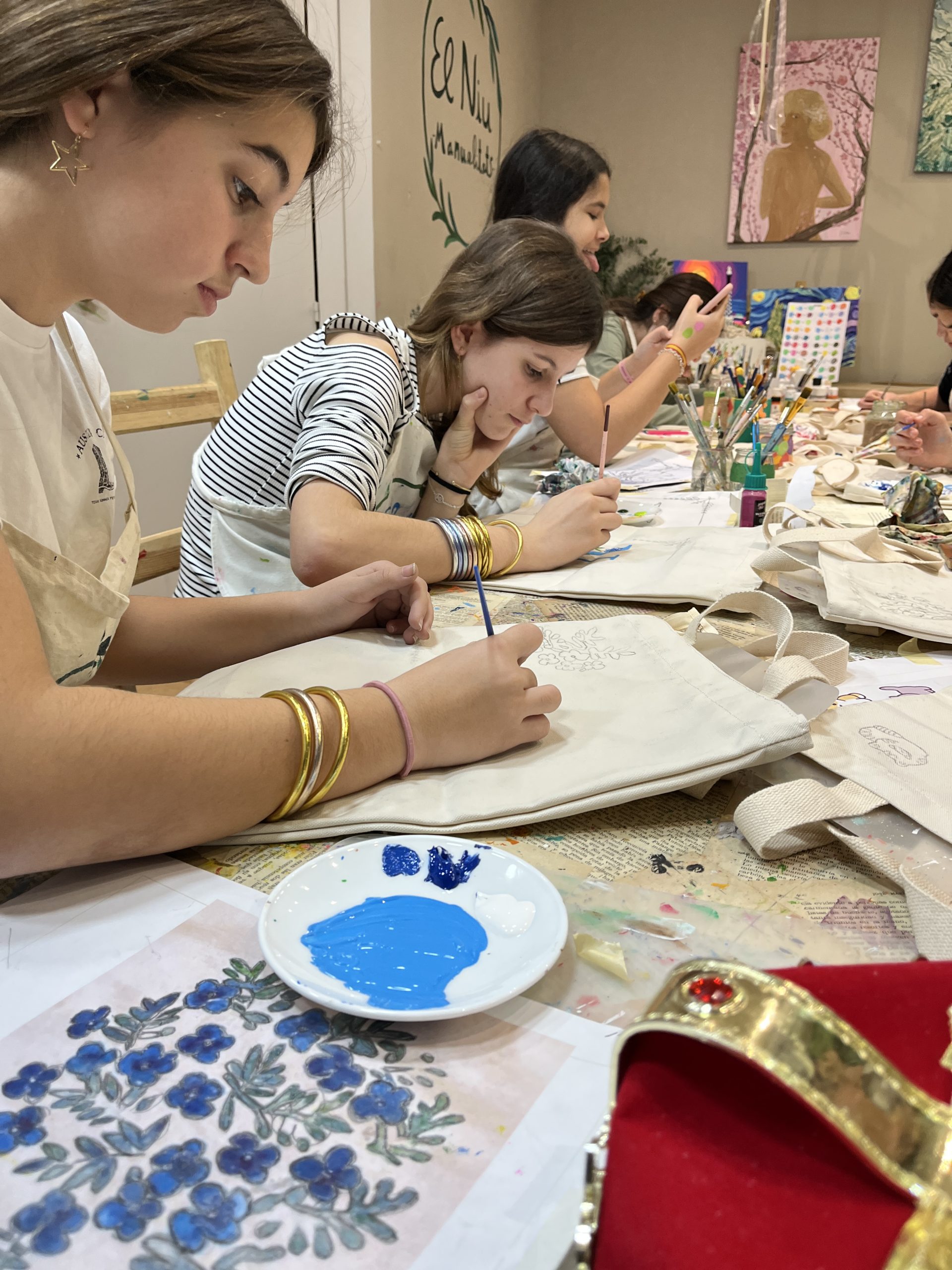 Mujer pintando una tote bag con pintura textil y pincel en un taller de pintar tote bag en Barcelona.